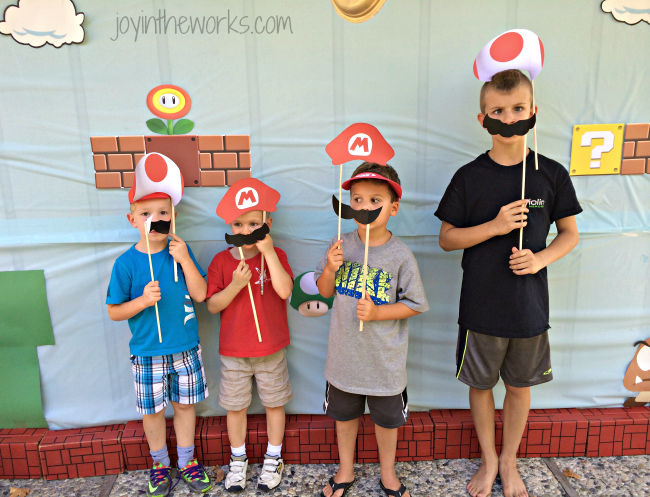 The boys using the photo props for the Super Mario backdrop