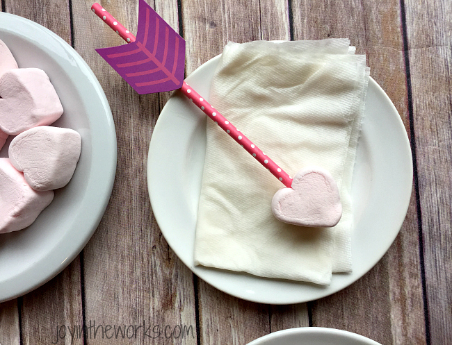 Easy Valentine treat: Cupid's Marshmallow Arrows with dipped and coated heart marshmallows on an arrow straw! No candy dipping necessary however- simply add sprinkles for a festive Valentine sweet! Perfect for a class Valentine party or a Valentine's Day gift!