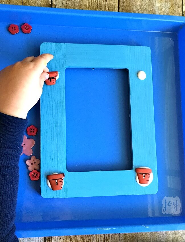 Such an easy Mother's Day gift! To mkae a Mother's Day Flower Button Frame simply paint a frame, add flower buttons (and flower pot buttons if you are lucky enough to find them!) and add stems! So easy that a kid not only can make it, but should make it as a gift for a mom or a grandmother!