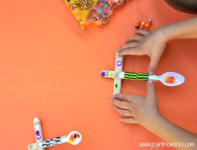 The perfect Halloween STEM activity is a Candy Corn Catapult! Even better? Try launching the candy corn, eyeballs and mini-pumpkins into cauldron targets!