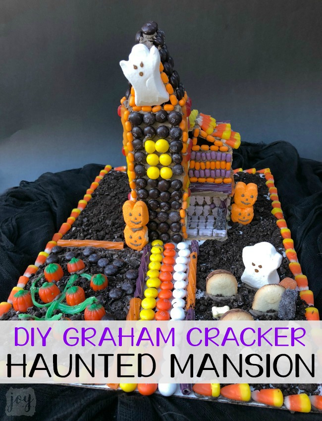 Forget the store bought Halloween Gingerbread House! Make a DIY Graham Cracker Haunted Mansion covered with candy instead! Step-by-step instructions available for how to make your own Halloween Graham Cracker House! Makes the perfect family fun activity after all the pumpkins are carved! Or even better? Make one with all of your leftover Halloween Candy! #halloween #halloweencandy #leftoverhalloweencandy #gingerbreadhouse #candyhouse #grahamcrackerhouse #hauntedhouse #hauntedmansion #halloweengingerbreadhouse #halloweengrahamcrackerhouse #diygingerbreadhouse #grahamcrackerhauntedmansion #gingerbreadhauntedmansion #familyfun #fallfamilyfun #fall