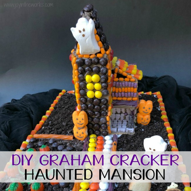 Forget the store bought Halloween Gingerbread House! Make a DIY Graham Cracker Haunted Mansion covered with candy instead! Step-by-step instructions available for how to make your own Halloween Graham Cracker House! Makes the perfect family fun activity after all the pumpkins are carved! Or even better? Make one with all of your leftover Halloween Candy! #halloween #halloweencandy #leftoverhalloweencandy #gingerbreadhouse #candyhouse #grahamcrackerhouse #hauntedhouse #hauntedmansion #halloweengingerbreadhouse #halloweengrahamcrackerhouse #diygingerbreadhouse #grahamcrackerhauntedmansion #gingerbreadhauntedmansion #familyfun #fallfamilyfun #fall